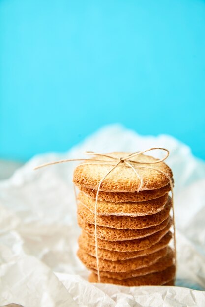 Column of tasty cookies tied with rope for gift on turquose backdrop