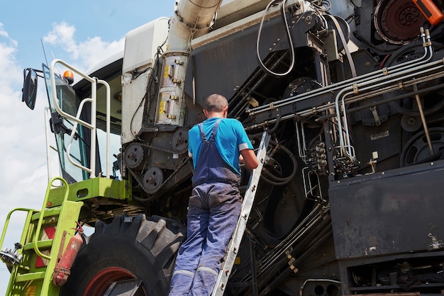 Combine machine service, mechanic repairing motor outdoors.