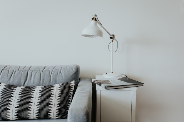 Free Photo comfortable couch in a modern house with a lamp on a little white shelf and a book with a waterfall