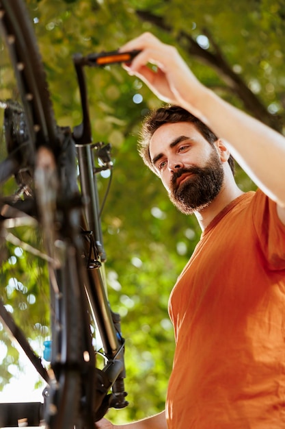 Committed energetic man finetunes and adjusting bike pedals in home yard Closeup shot of athletic caucasian male meticulously examining and correcting damages on bicycle crank arm