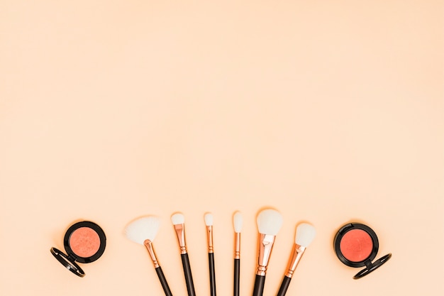 Compact face powder with white makeup brushes on colored backdrop