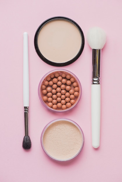 Free Photo compact powders; bronzing pearls and makeup brushes on pink surface