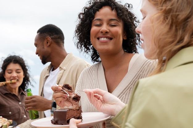 Companions eating outdoors cake and barbeque during party