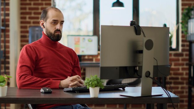 Company employee talking to people on online videoconference, using webcam on computer to attend business meeting. Young person chatting on videocall conference for remote discussion.