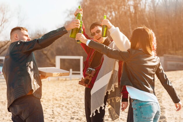 Company of smiling friends having fun with beer in open air