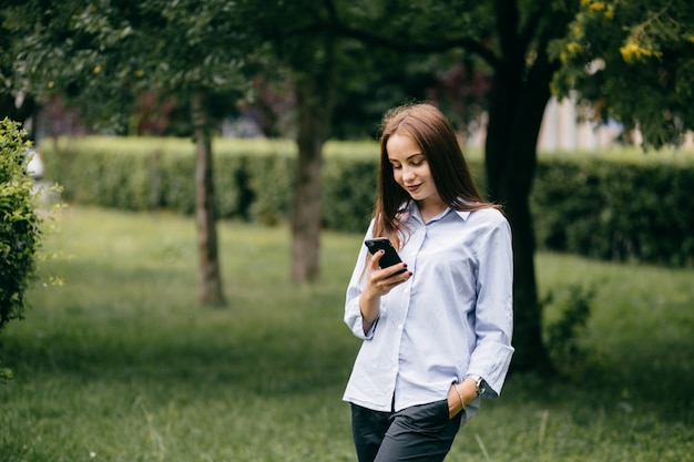 company of young friends with smartphones walking in city