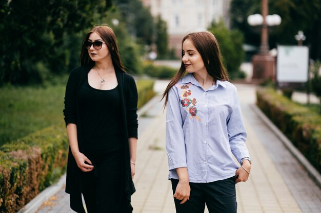 company of young friends with smartphones walking in city