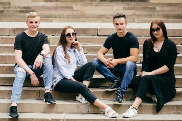 company of young friends with smartphones walking in city