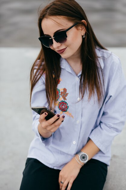 company of young friends with smartphones walking in city