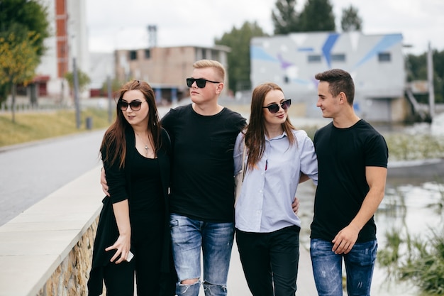 company of young friends with smartphones walking in city