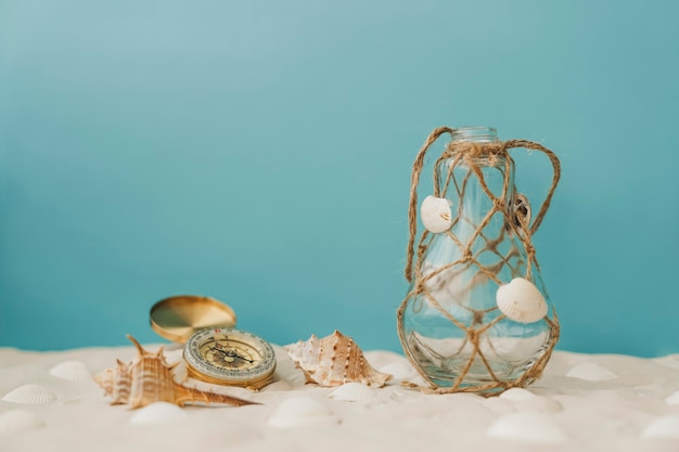 Free photo compass and bottle on the sand