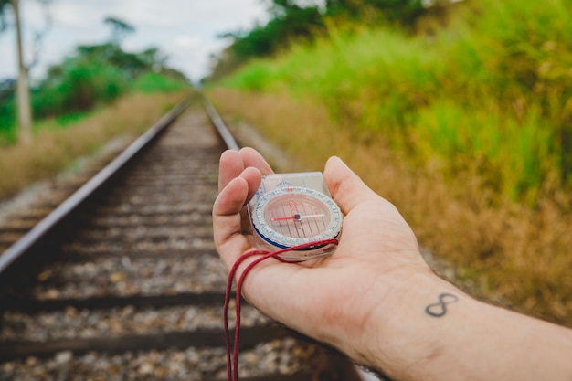 Compass in tattooed hand on train tracks