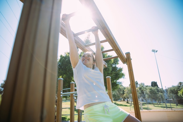 Competitive young woman exercising on monkey bars