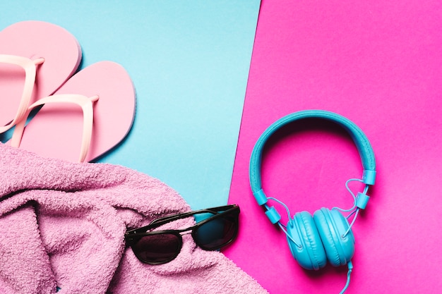 Composition of beach accessories and headphones on multicolored background