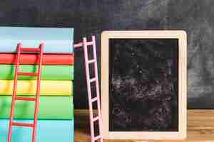 Free photo composition of books with ladder near chalkboard