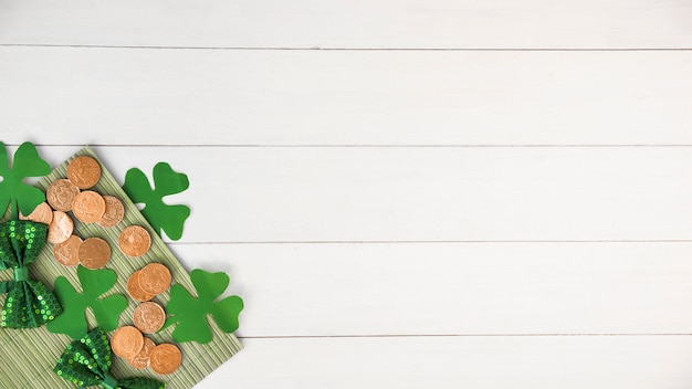 Free Photo composition of bow ties near coins and green paper clovers on board