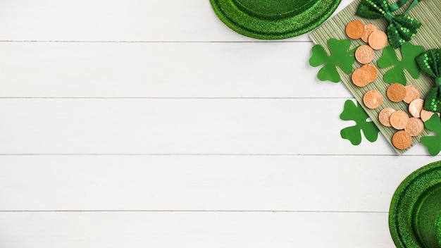 Free photo composition of bow ties near hats, coins and green paper clovers on board