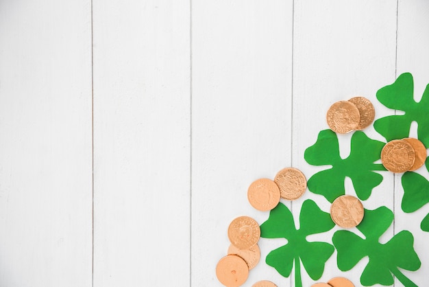 Free photo composition of coins and green paper clovers on board