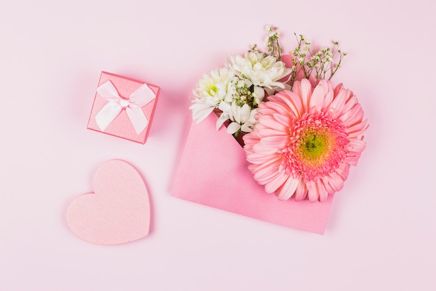 Free photo composition of fresh flowers in envelope near present and ornamental heart