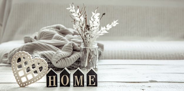 Free photo composition in hygge style with the wooden word home, decor details and a knitted element