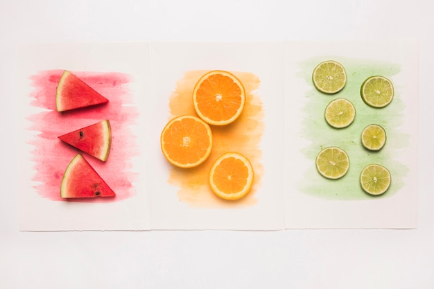 Free Photo composition of juicy cut fruits on colored watercolor splash