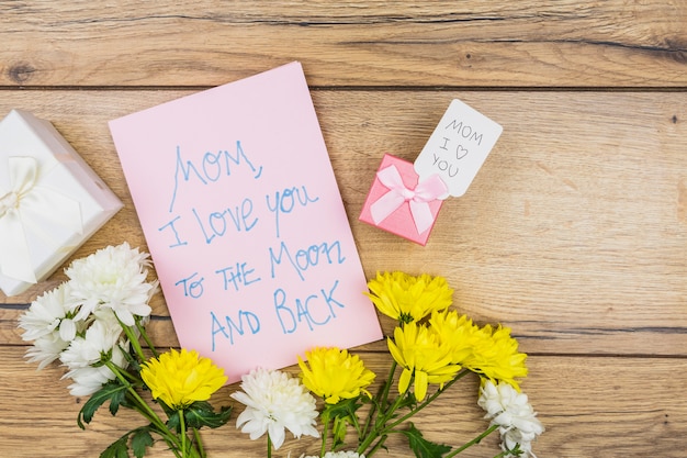 Composition of paper with words near flowers and presents