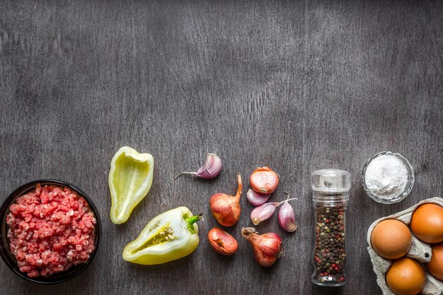 Composition of raw meat with vegetables and spice on wooden background