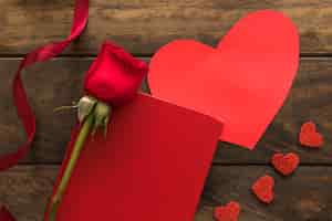 Free photo composition of red flower near ribbon, hearts and paper