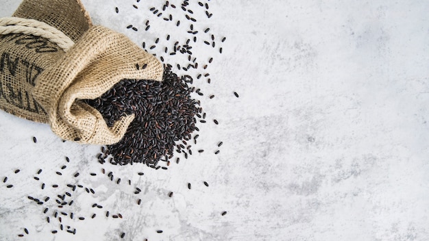 Free photo composition of scattered black rice in sack