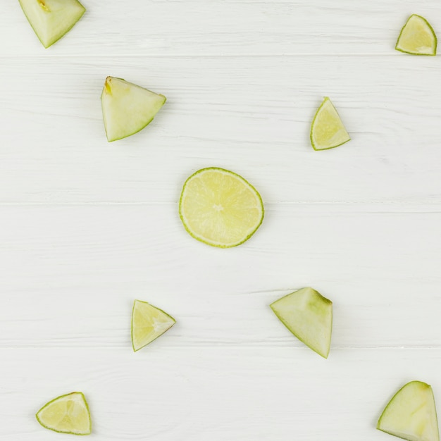 Composition of sliced apples and lime on white background