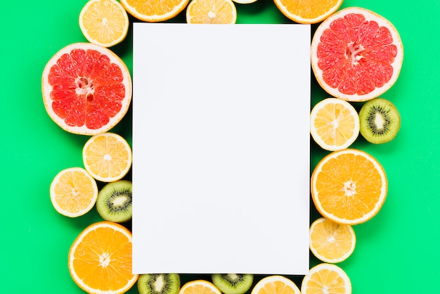 Free photo composition of sliced colorful exotic fruits with blank paper