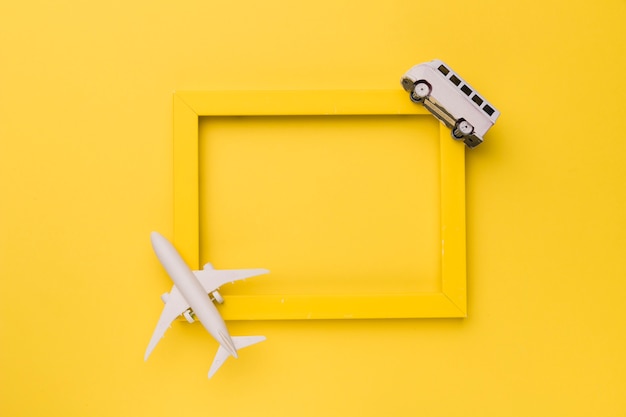 Composition of small white plane and bus on yellow frame