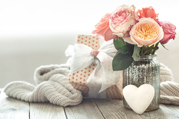 Free photo composition with a bouquet of roses in a glass vase with a gift box