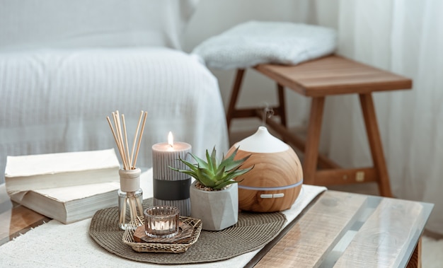 Composition with incense sticks, diffuser, candles and books on the table in the interior of the room.