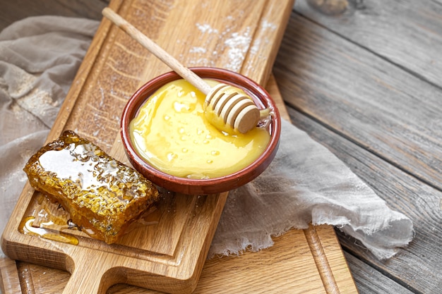 Composition with natural honey and honey dipper on wooden background close up.