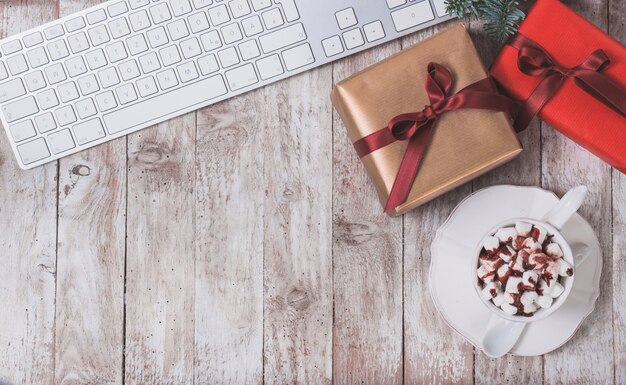 Computer keyboard, christmas gift and cup with marshmallows