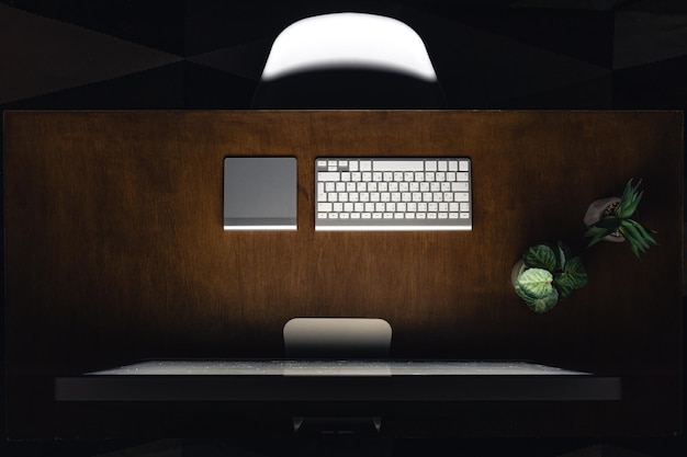 Free photo computer keyboard and cup of tea on a wooden table at night