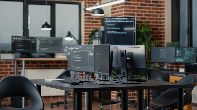 Computer screens running programming code in empty software developing agency office and computers parsing data algorithms in background. Neural network servers cloud computing in data room.