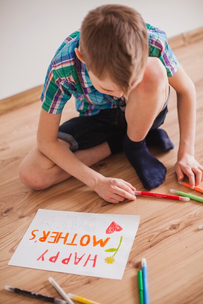 Concentrated boy using colored pencils for his poster