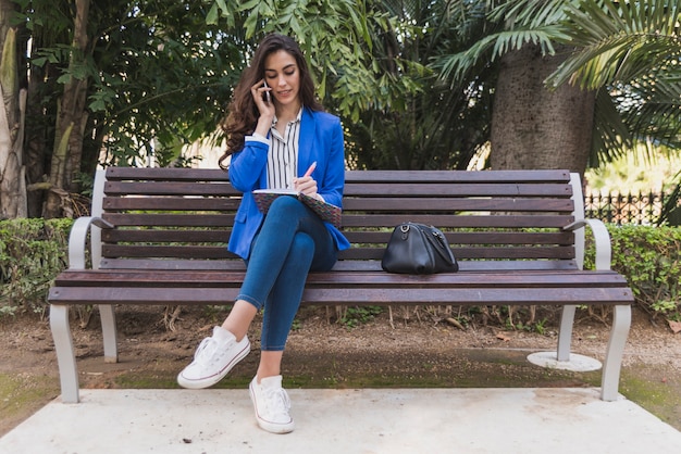 Free Photo concentrated businesswoman working on a park bench