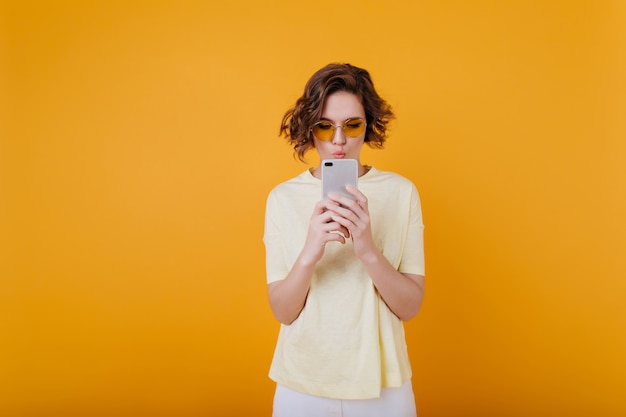 Concentrated curly girl texting message on yellow space