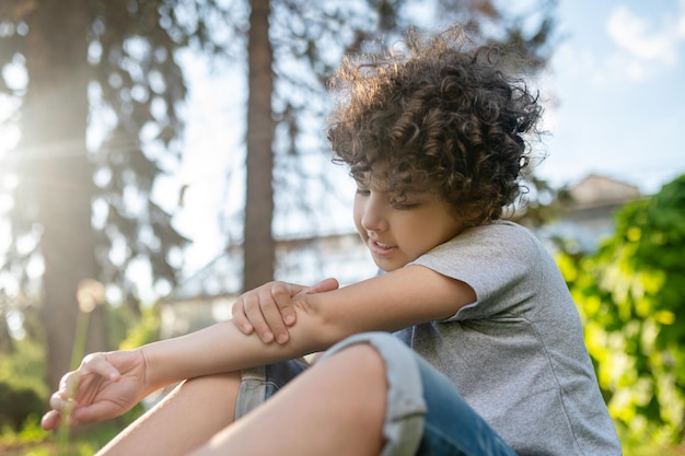 Free Photo concentrated kid examining his damaged elbow joint