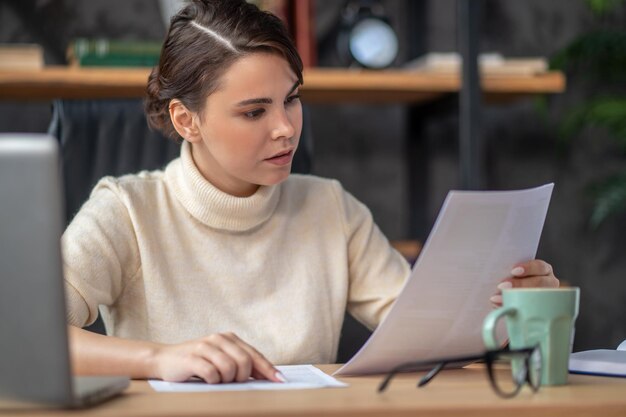 Concentrated lady examining documentation at the desk