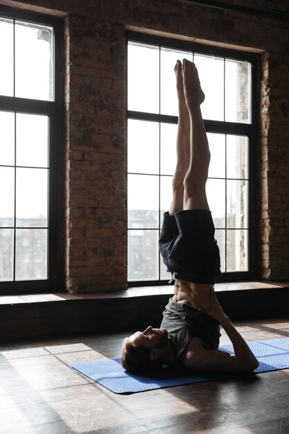 Concentrated strong sportsman in gym make yoga sport exercises