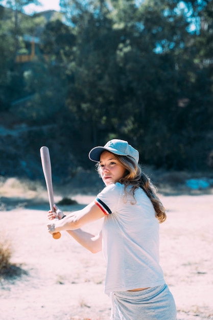 Concentrated teen student swinging baseball bat