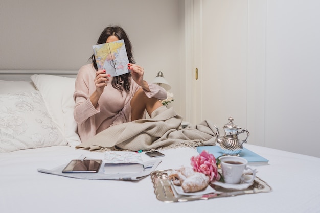 Concentrated woman checking a map in her bedroom