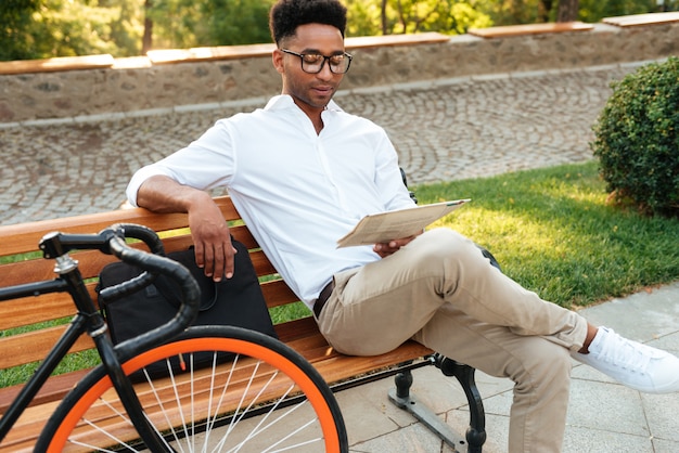 Concentrated young african man reading newspaper.