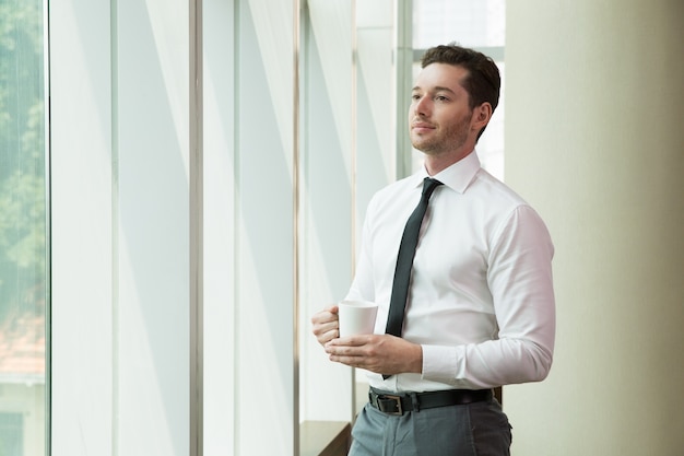 Concentrated young businessman looking out window