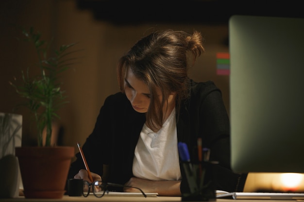 Free photo concentrated young lady designer sitting in office