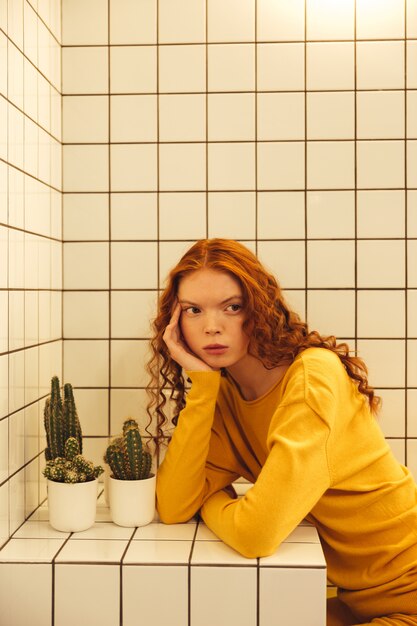 Concentrated young redhead curly lady sitting in cafe